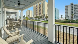 A covered outdoor area with wooden furniture, a view of tall buildings, and a road in the background.