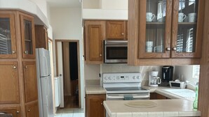 Una cocina con gabinetes de madera, un refrigerador de acero inoxidable, un horno y una cafetera.