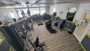Une salle de sport équipée de divers appareils d’exercice, notamment des tapis de course, des vélos elliptiques et des appareils de musculation.