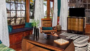 A room with a wooden bench, a television, and a view of palm trees through large windows. - Villas de Isla Bonita  - B2 (San Pedro)