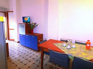 Un pequeño comedor con una mesa, sillas, un televisor y un armario.
