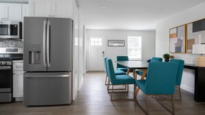 A modern kitchen with stainless steel appliances, teal chairs, and a dining table. - 3 BR in the Heart of Middletown, Minutes from Beach! (Middletown)