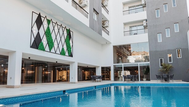 Un hotel modern amb piscina, diverses plantes i un disseny de paret distintiu verd i negre.