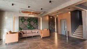 Un vestíbul ampli amb un sofà modern, una paret decorativa i una escala.