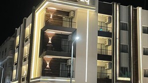 Un edifici modern amb el rètol “TK SUITES” que indica que és un hotel. Té diversos balcons i aparells d'aire condicionat visibles a l'exterior.