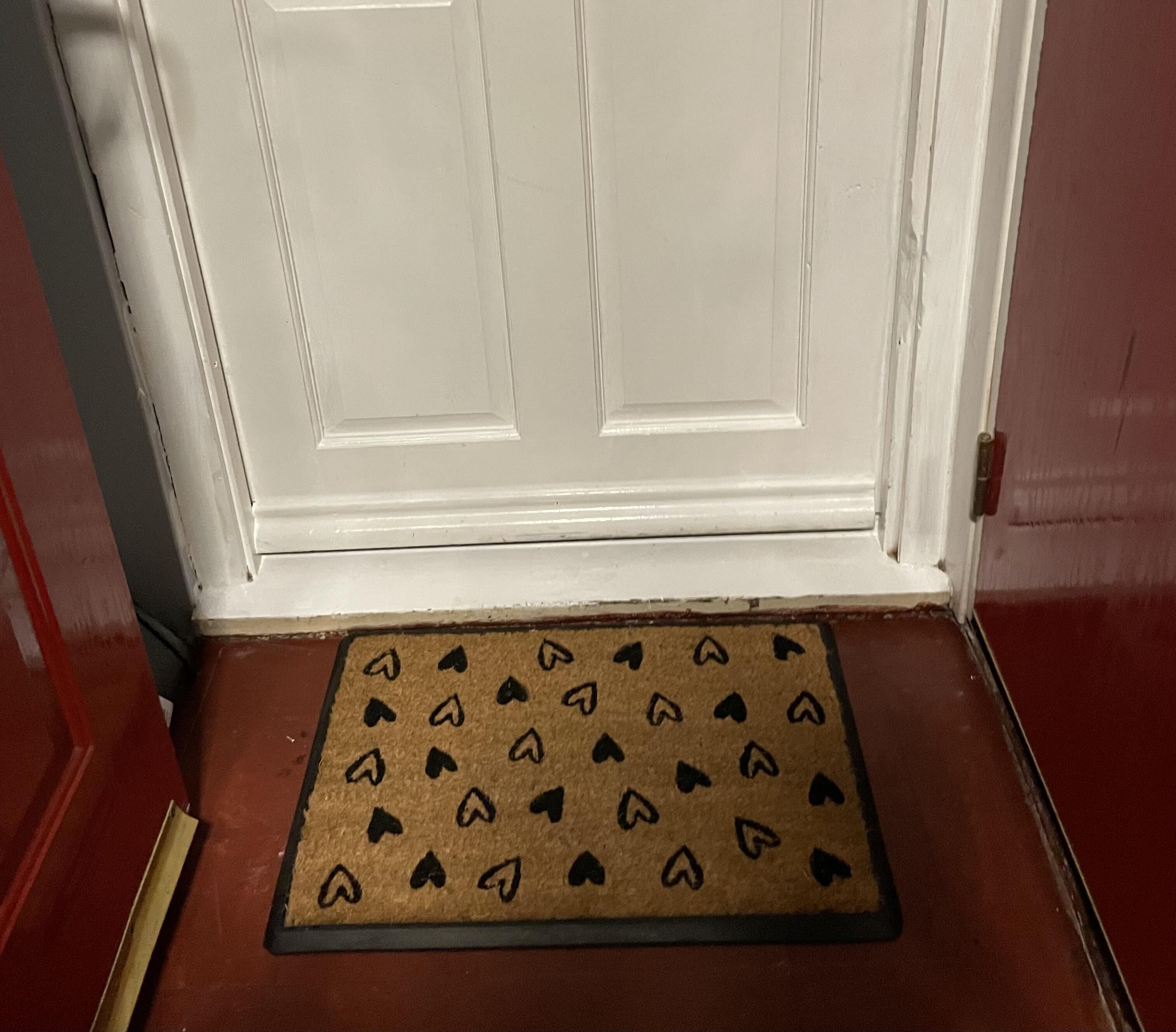 A door with a white frame and a brown doormat with black arrow patterns.