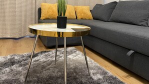 A modern living room with a grey sofa, a round gold table with a black vase, and a grey shag rug. - Walk to Lcy Airport/ Excel /dlr 1Br Flat (London)