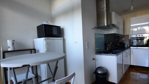 Eine kompakte Küche mit Mikrowelle, Herd und Spüle. Es ist ein kleiner Esstisch mit Stühlen vorhanden.