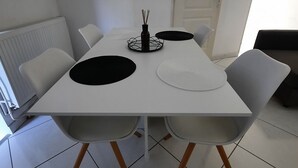 Ein moderner Essbereich mit einem weißen Tisch, vier Stühlen und einem dekorativen Mittelstück.