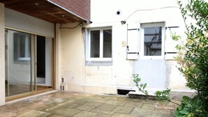 Ein Wohngebäude mit Schiebeglaseingang, einem kleinen Fenster und einer Beton-Terrasse.