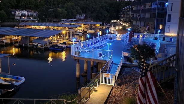 Een jachthaven met aangemeerde boten, een overdekte helling voor boten en een uitkijkpunt met ligbedden.