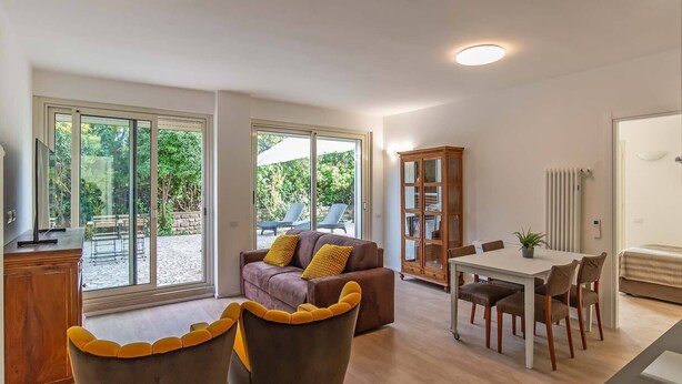 A modern living room with a sofa, a dining table with chairs, and a cabinet.