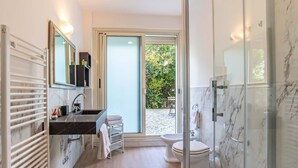 A modern bathroom with a glass shower enclosure, a sink with a marble countertop, and a toilet.