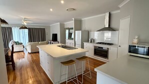 A modern kitchen with a central island, white cabinetry, and a built-in oven.