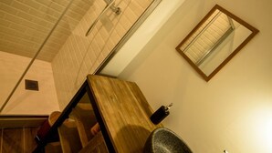 Une salle de bain avec un meuble-lavabo en bois, un grand lavabo, une douche avec une porte en verre et un miroir au mur.