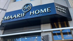 Een meerlaags gebouw met een bord waarop 'MAARIF HOME APPARTHOTEL - RESTAURANT' staat.