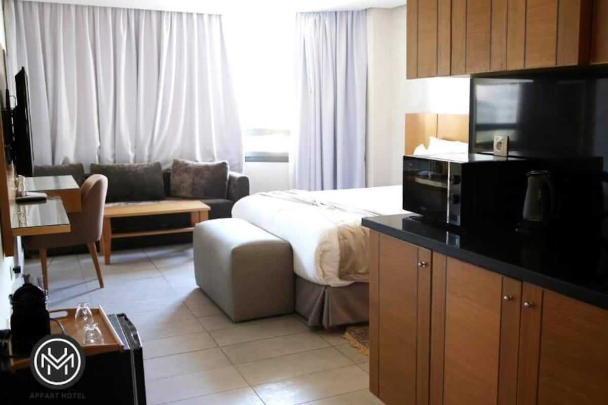Une chambre d’hôtel compacte comprenant un coin cuisine, un canapé, un lit et un espace repas.
