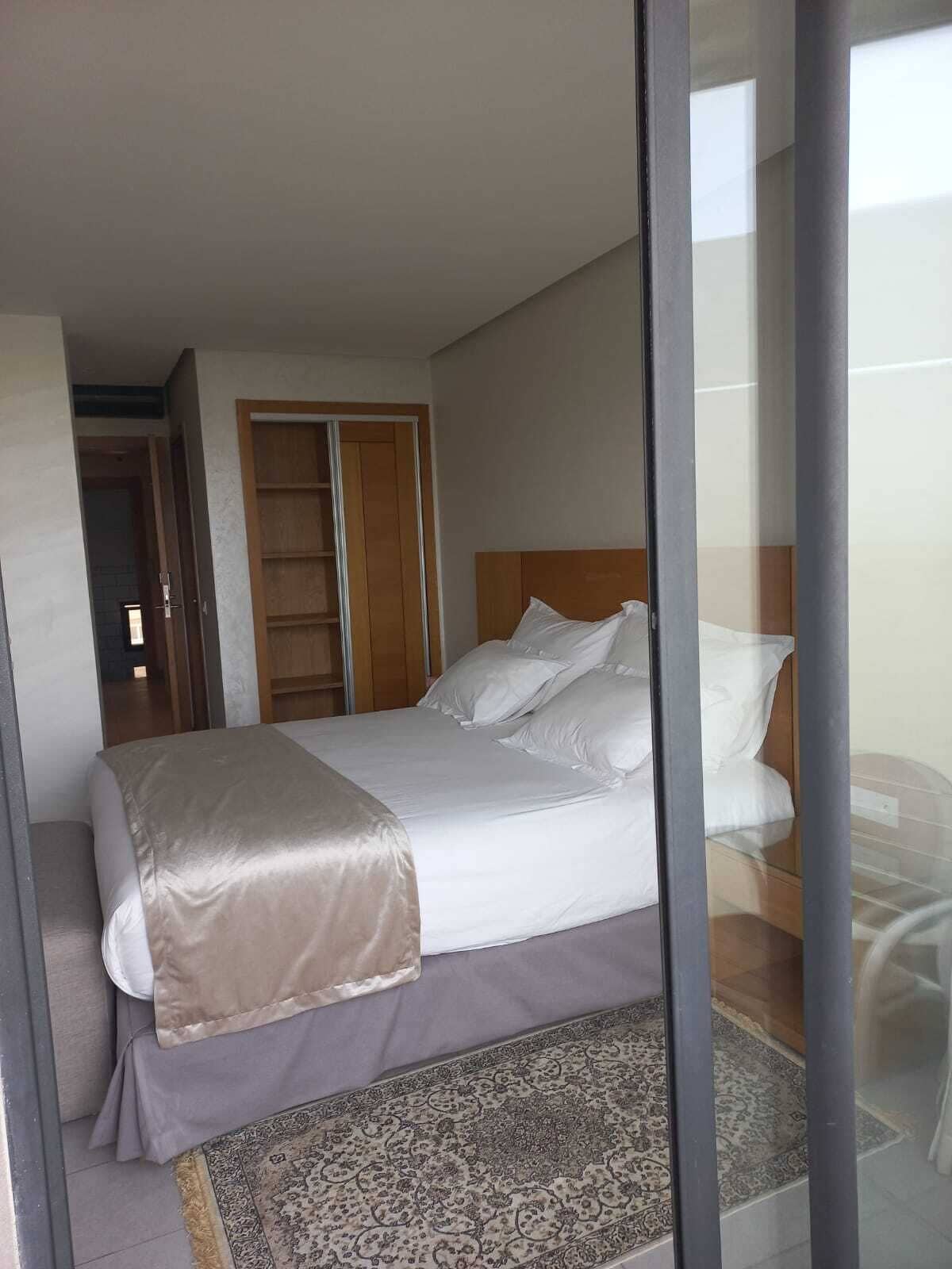 Ein Hotelzimmer mit einem Bett, einem Holzschrank und einem gemusterten Teppich.