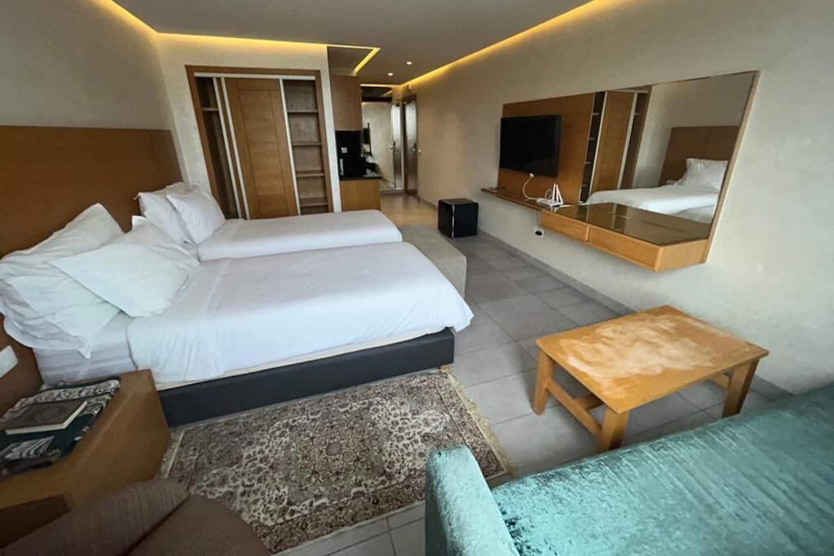 Une chambre d’hôtel avec un grand lit, une télévision, un miroir et une petite table.