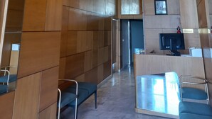 Een moderne hotellobby met houten paneelwanden, een receptiebalie en zithoeken.