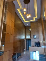Un moderno vestíbulo de hotel con paneles de madera, una recepción y zonas de estar.