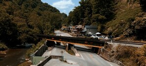 A bridge over a river with a road underneath, surrounded by forested hills and a few buildings. - Luxury ATV lodging with beautiful view, sleeps 11. (Welch)