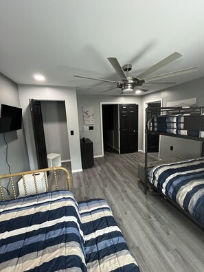 A bedroom with two beds, a ceiling fan, a TV, and a door leading to another room. - Luxury ATV lodging with beautiful view, sleeps 11. (Welch)