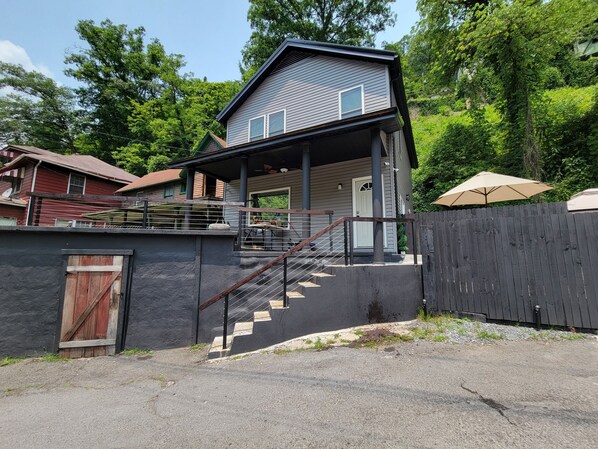 A two-story house with a covered porch and a staircase leading to the entrance. - Luxury ATV lodging with beautiful view, sleeps 11. (Welch)