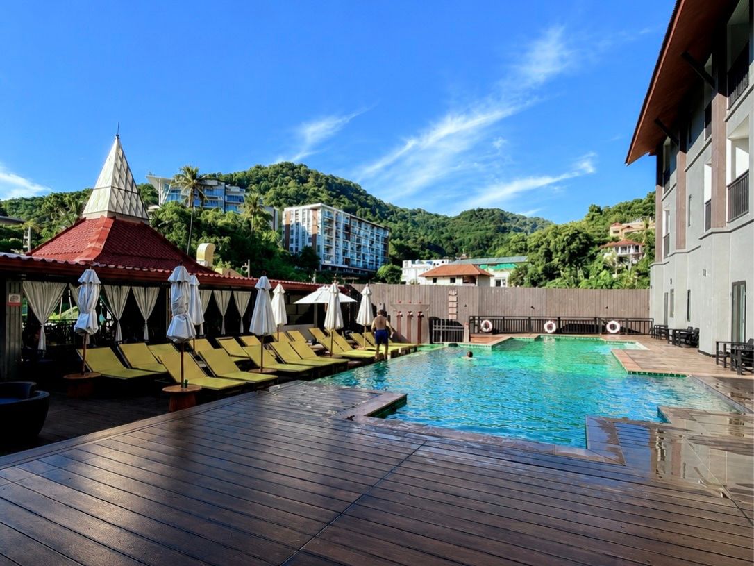 Una piscina con tumbonas y una terraza de madera.