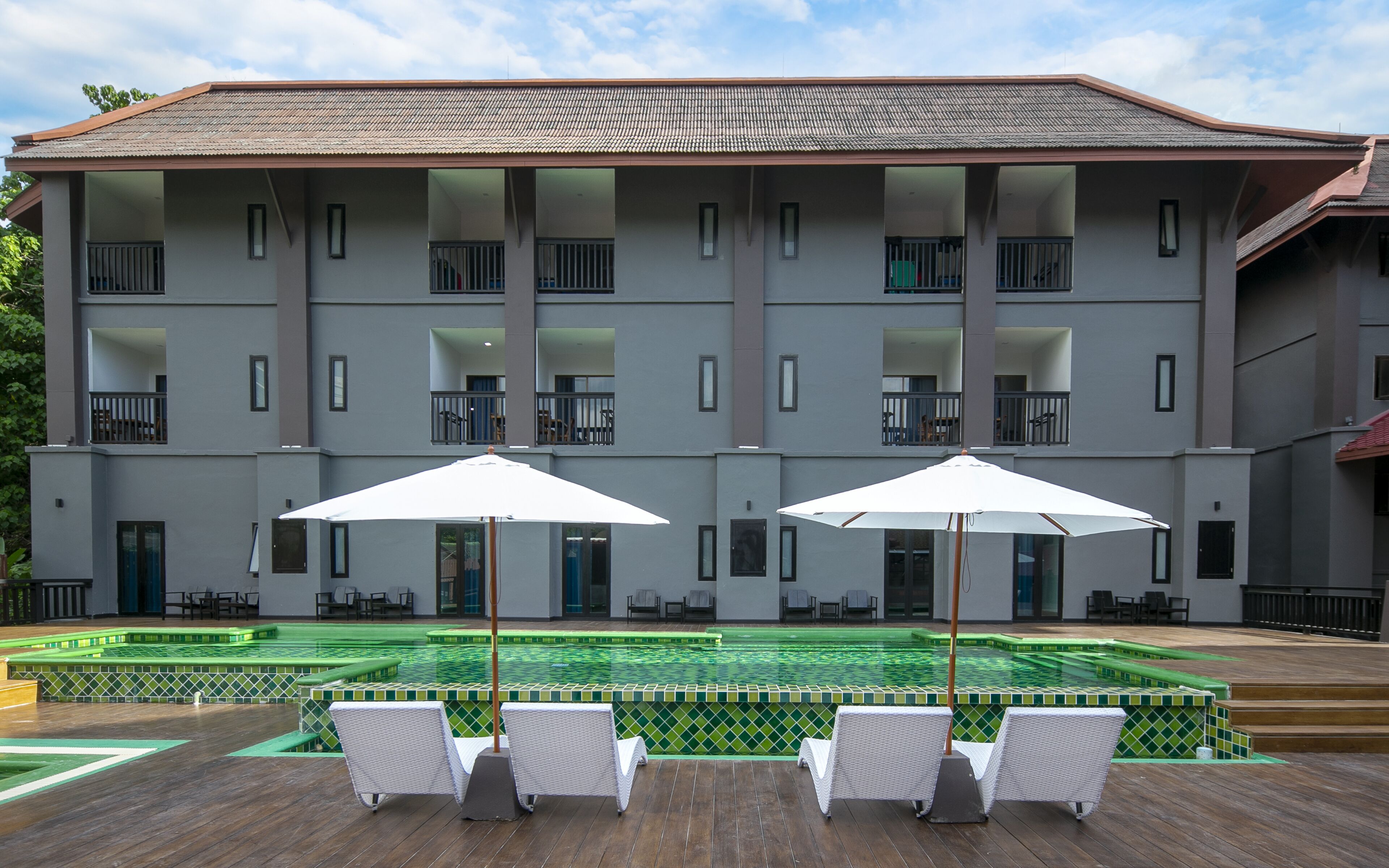 Ein Hotel mit Swimmingpool, Außenbereich zum Sitzen und einem großen Gebäude mit Balkonen.