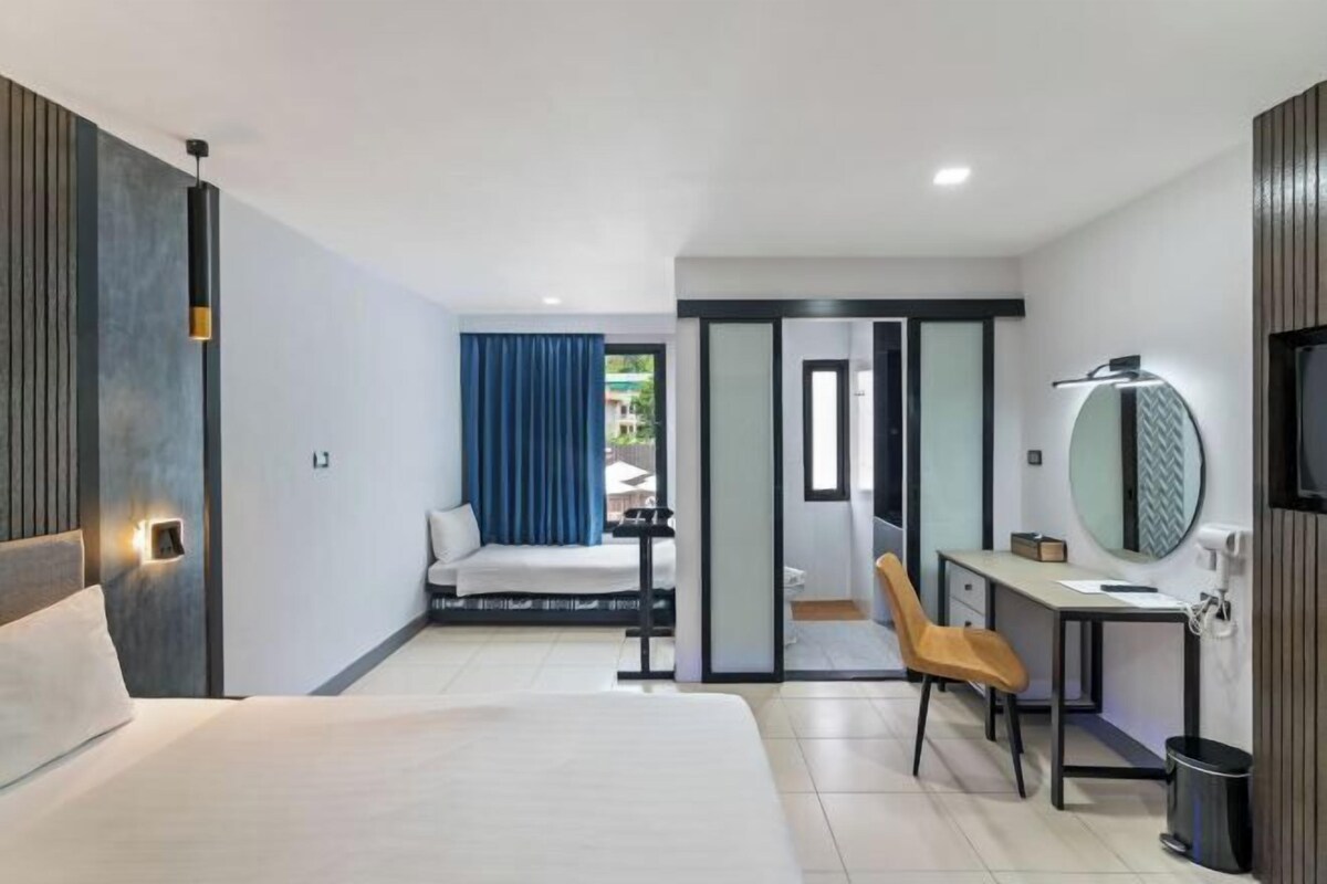 A modern hotel room with a bed, desk, chair, and a television.