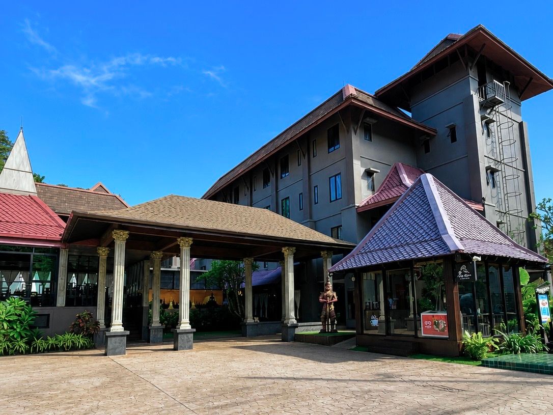 Um hotel com entrada coberta, uma estátua e um edifício alto com telhado vermelho.
