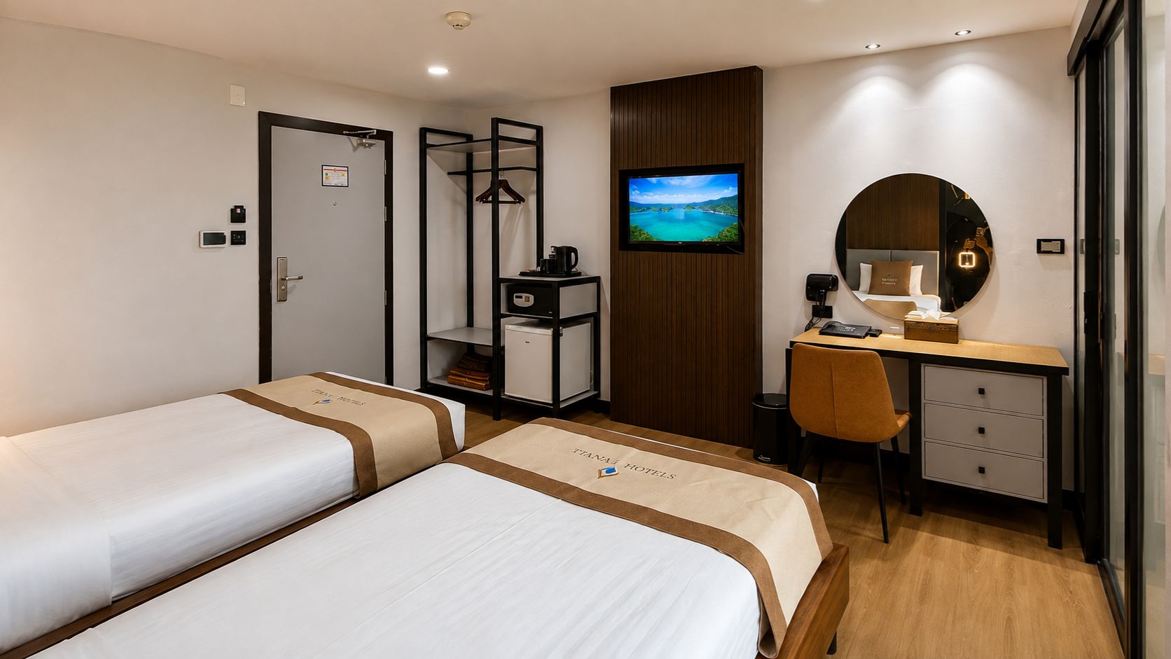 A hotel room with two beds, a desk, a chair, a TV, and a wardrobe.