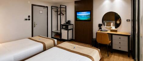 A hotel room with two beds, a desk, a chair, a TV, and a wardrobe.