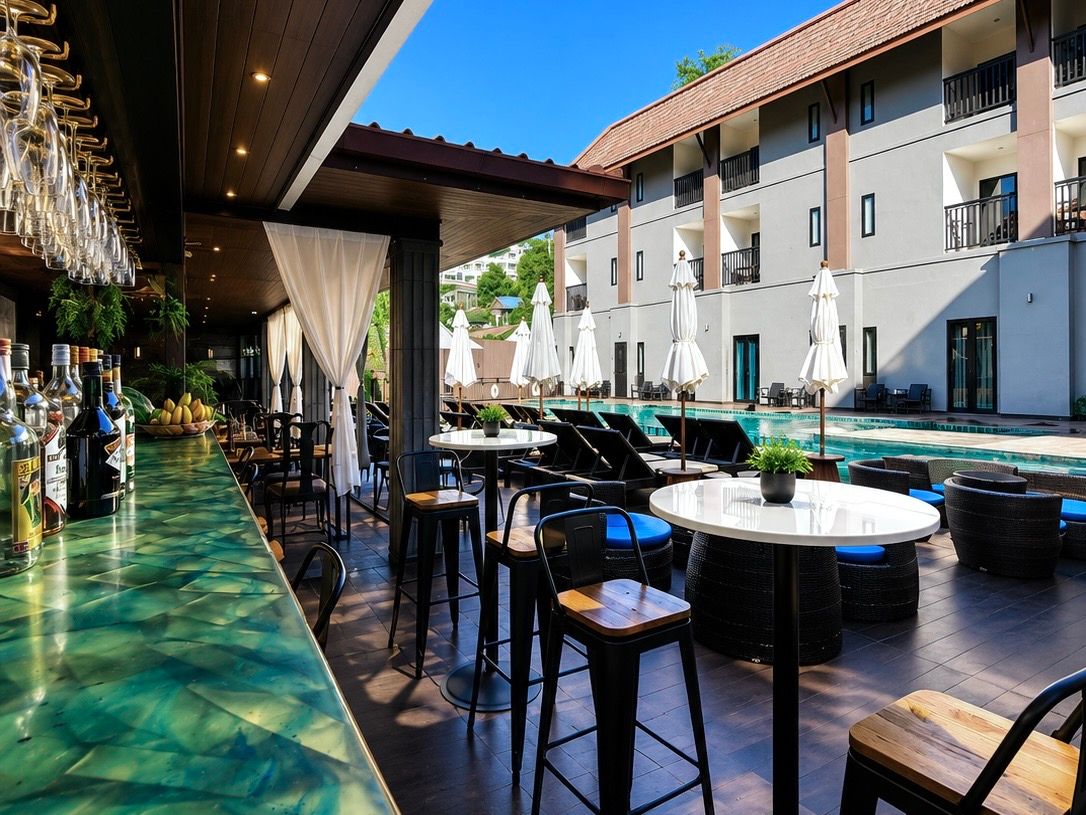 A rooftop bar with outdoor seating, a pool, and a building with balconies.