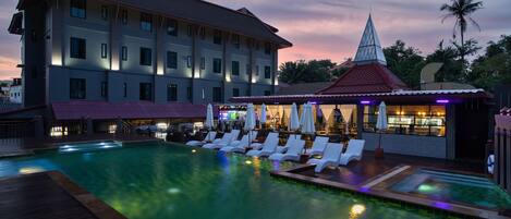Ein Hotel mit Schwimmbad, Liegestühlen und Barbereich.