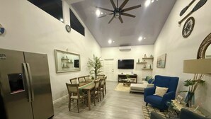 A modern living room with a dining area, a blue sofa, a ceiling fan, and a flat-screen TV. - Villa Cielo, Casa de Playa Frente al mar (Provincia de Puntarenas)