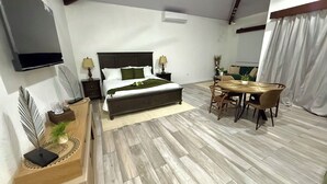 A bedroom with a bed, bedside tables, a TV, a dining area with a table and chairs, and a living area with a sofa. - Villa Cielo, Casa de Playa Frente al mar (Provincia de Puntarenas)