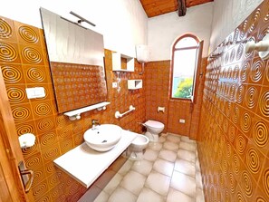 A bathroom with patterned walls, a sink, a toilet, and a mirror.