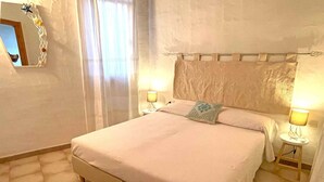 A bedroom with a bed, two bedside lamps, a mirror, and a curtain. - Villa Rosa dei Venti (Valledoria)