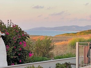 Un balcon avec vue sur la mer et les collines.