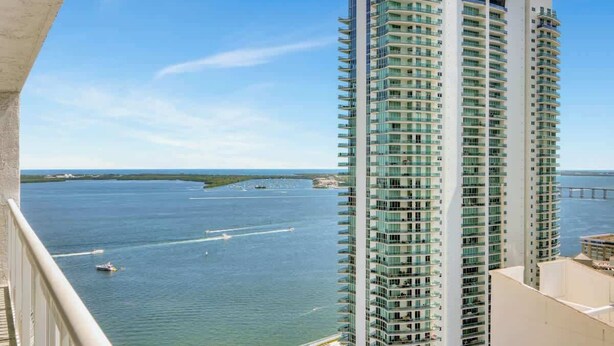 Un hotel moderno de gran altura con varios balcones que dan a una extensión de agua.