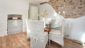 Een eetgedeelte met rieten stoelen, een glazen tafel en een stenen muur.
