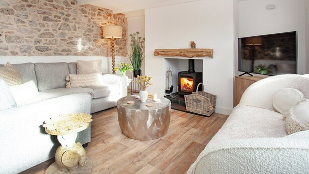 Een knusse woonkamer met een stenen muur, een open haard, een televisie en een comfortabele zithoek.