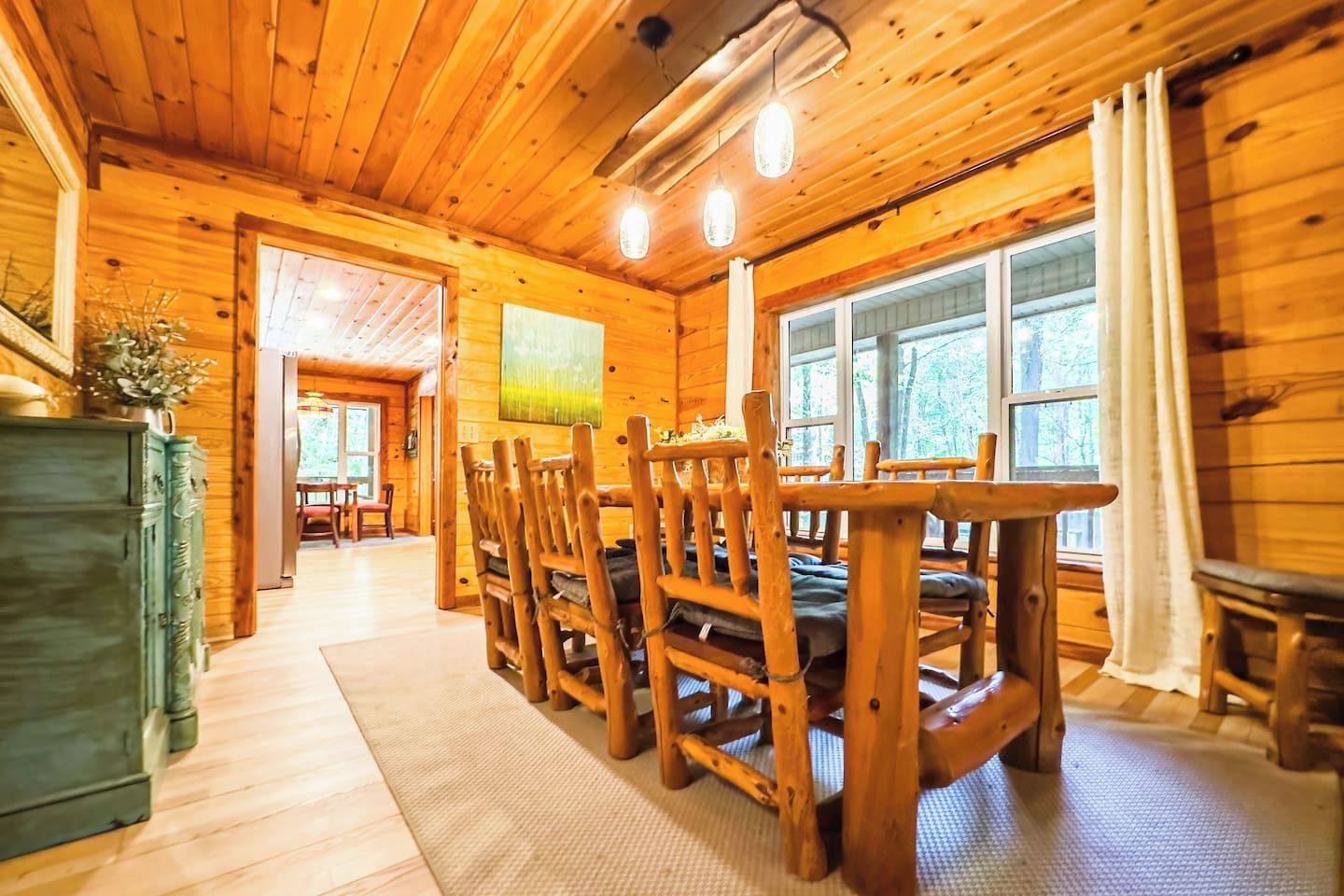 Un interior de madera con comedor, que incluye una mesa, sillas, un ventanal y vistas al exterior.