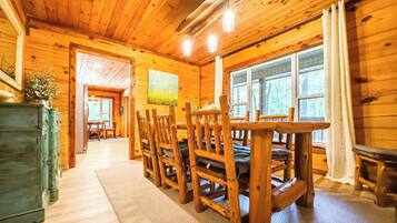 Un interior de madera con comedor, que incluye una mesa, sillas, un ventanal y vistas al exterior.