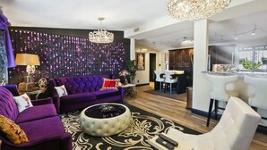 Uma sala de estar moderna com um sofá roxo, uma mesa de centro redonda e um lustre.