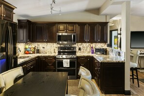 A modern kitchen with dark wood cabinets, stainless steel appliances, and a marble countertop.