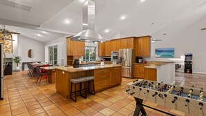 A modern kitchen with wooden cabinets, stainless steel appliances, and a foosball table. - Next to IMG Golf! Heated Pool, Spa, Game Room! (Bradenton)