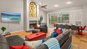 A spacious living room with a fireplace, comfortable seating, a dining area, and large windows offering a view of the outdoors. - Next to IMG Golf! Heated Pool, Spa, Game Room! (Bradenton)